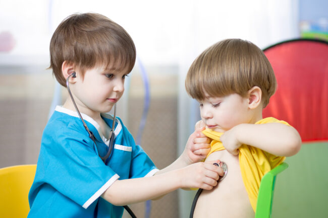 Child listening to another child’s chest with a stethoscope